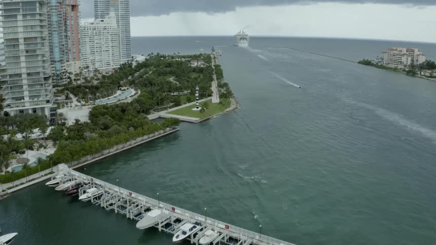A large boat drives in the ocean next to a city