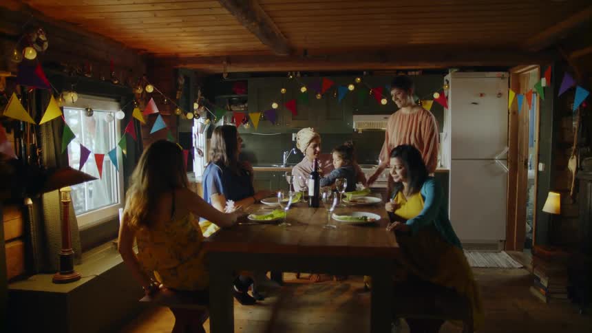 Five women and a child sitting around a kitchen table with party decorations on the wall