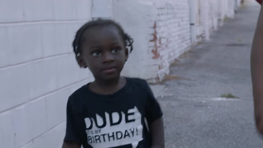 Children walk outside on the sidewalk