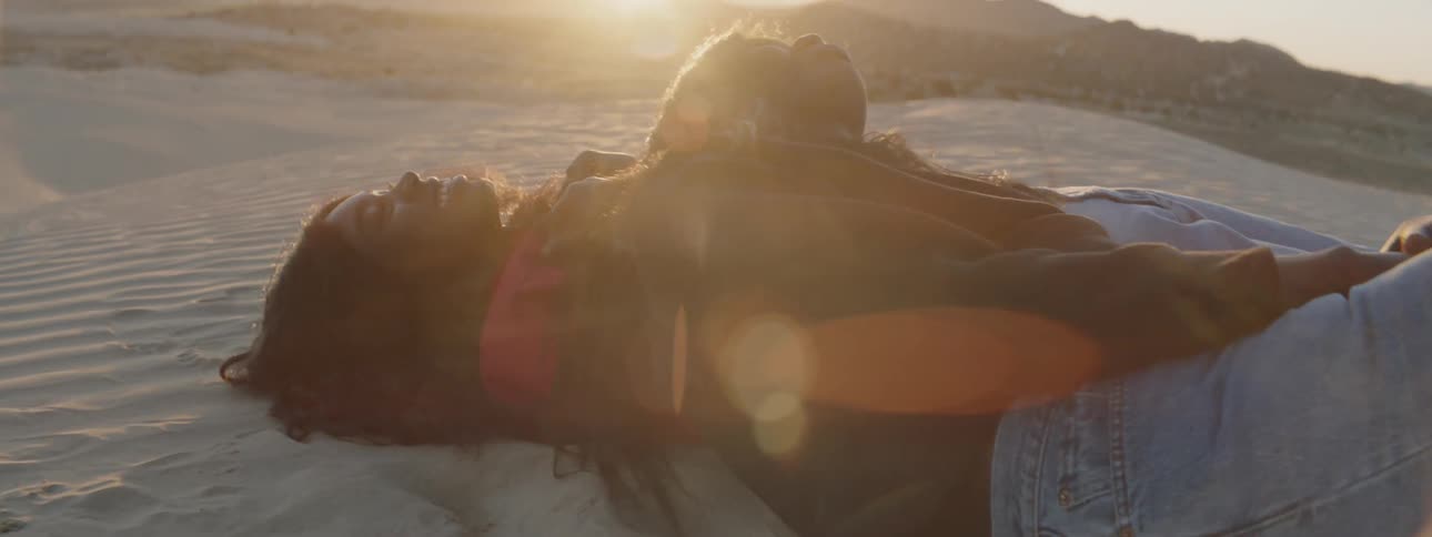 Two women lay in the desert and laugh