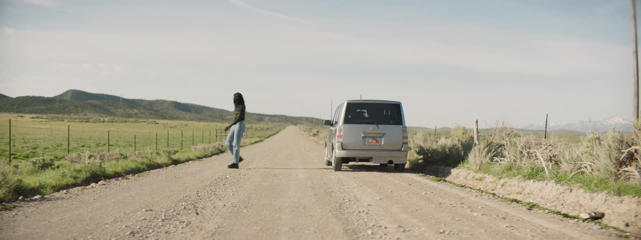 Woman gets out of a vehicle in the middle of a country road