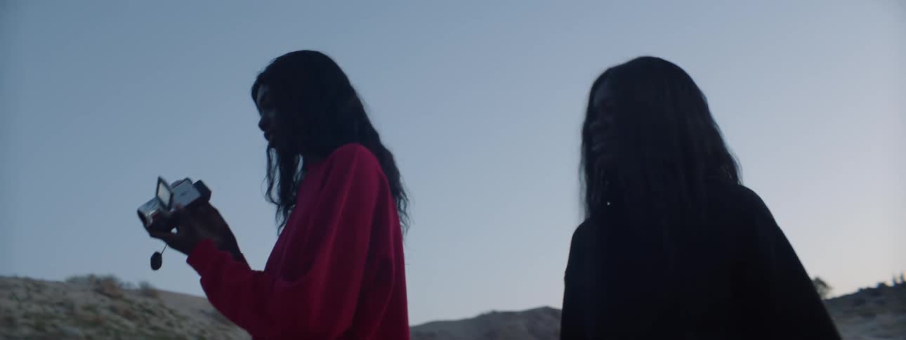 Two women walking around outside carrying a video camera