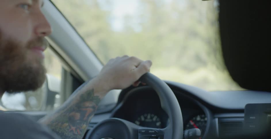 Man drives a car on a tree lined road