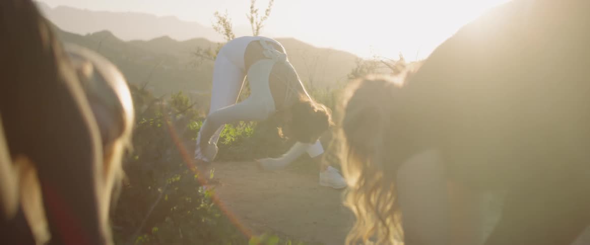 A group of women stretch outside under the sun