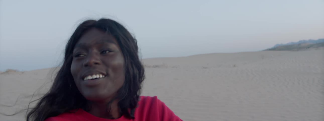 A woman sits in the desert and laughs