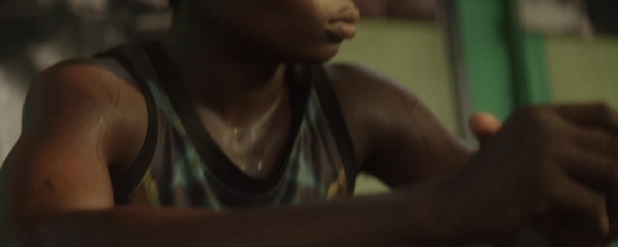 A young man sits pensively looking to the side as he's drenched in sweat