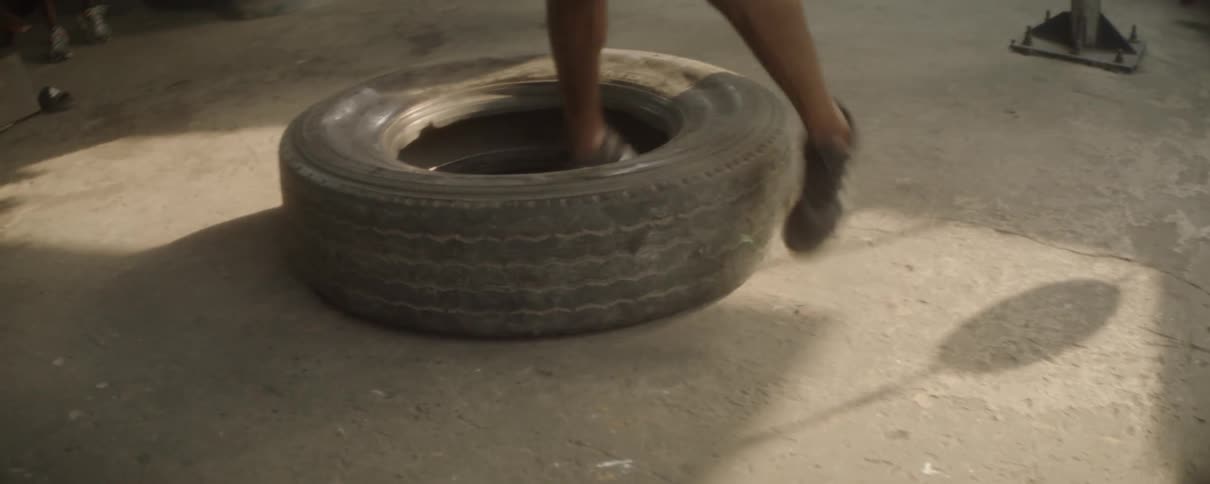 A man jumps in and out of a tire as a workout