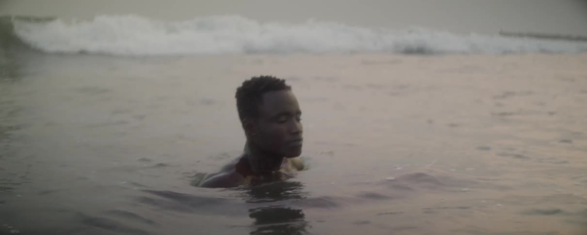 Man sits in the water and lets the waves wash over him