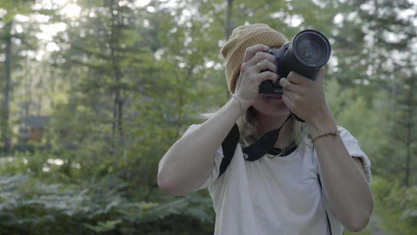 Woman takes pictures in the woods with a large camera