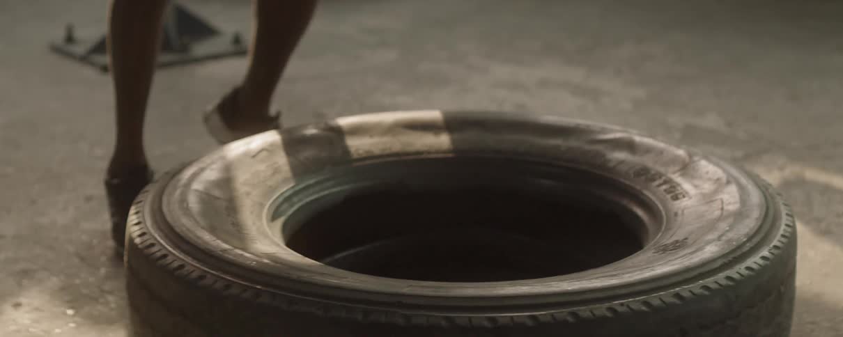 A man jumping on a tire in a gym