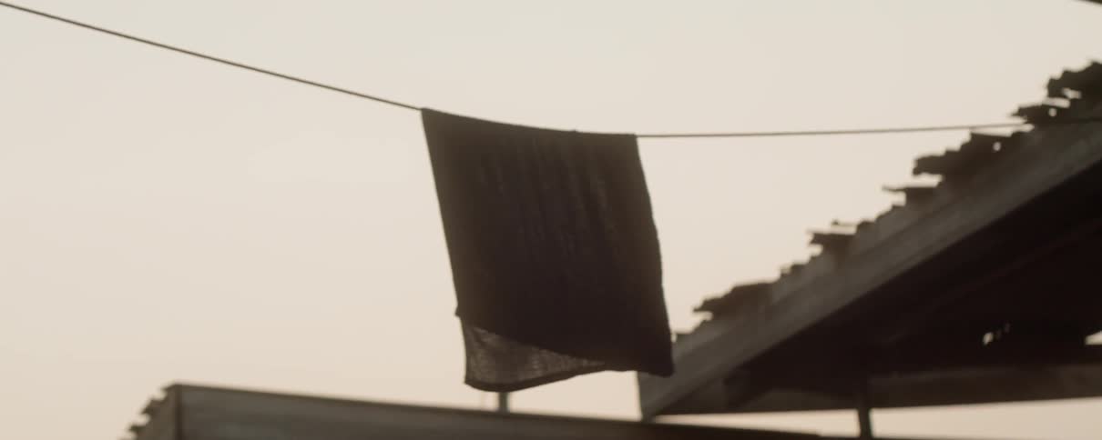 Blanket hangs on a clothesline outside and blows in the wind