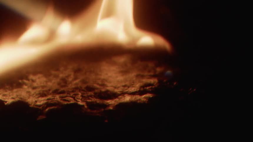 Fire burns brightly warping and bubbling the black material that's on fire