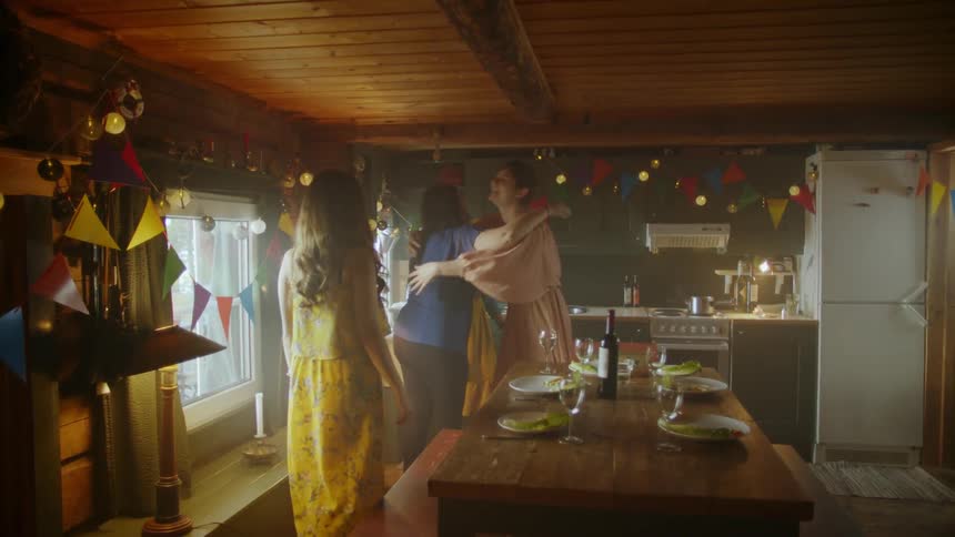 A group of women greeting each other in a kitchen