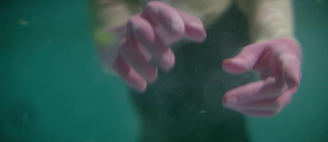 A woman reaches her arms underwater
