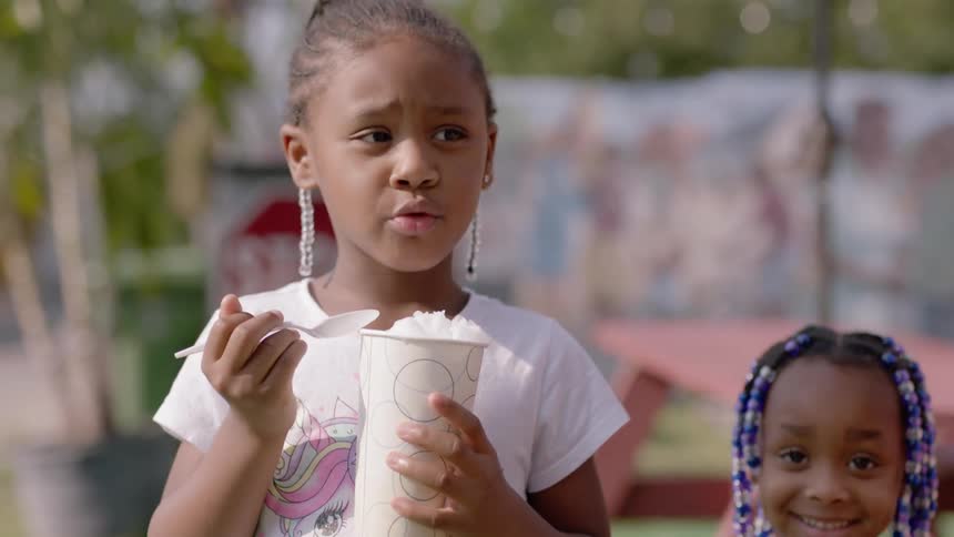 A young girl eats shaved ice outside