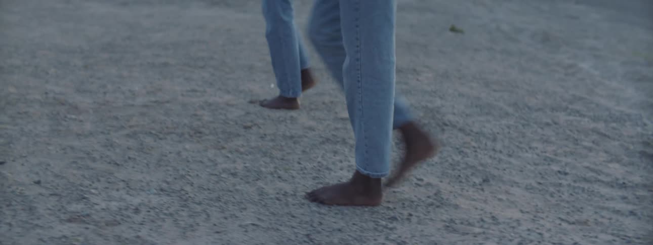 Two people walk barefoot in the desert
