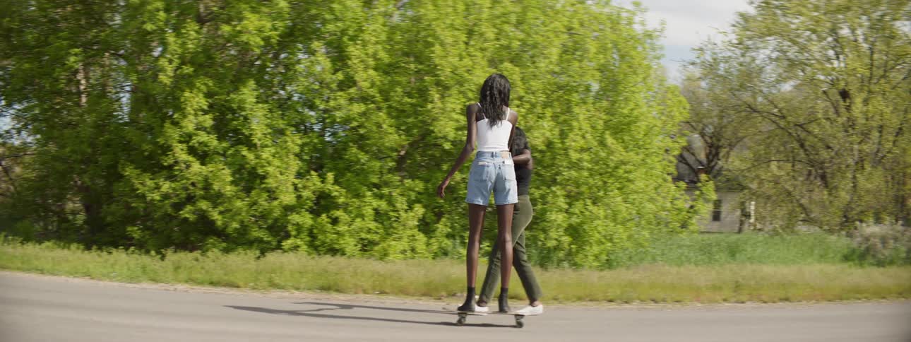 A woman riding on a skateboard next to her friend
