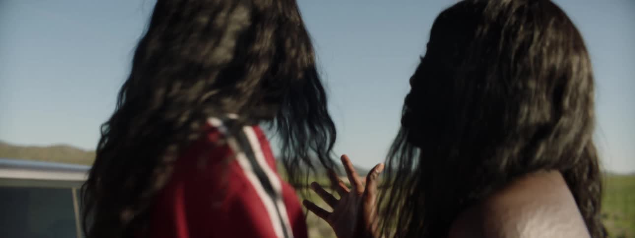 Girls argue while standing next to car