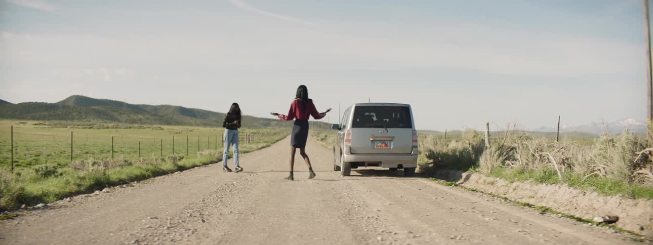 Females walking around a car looking for help