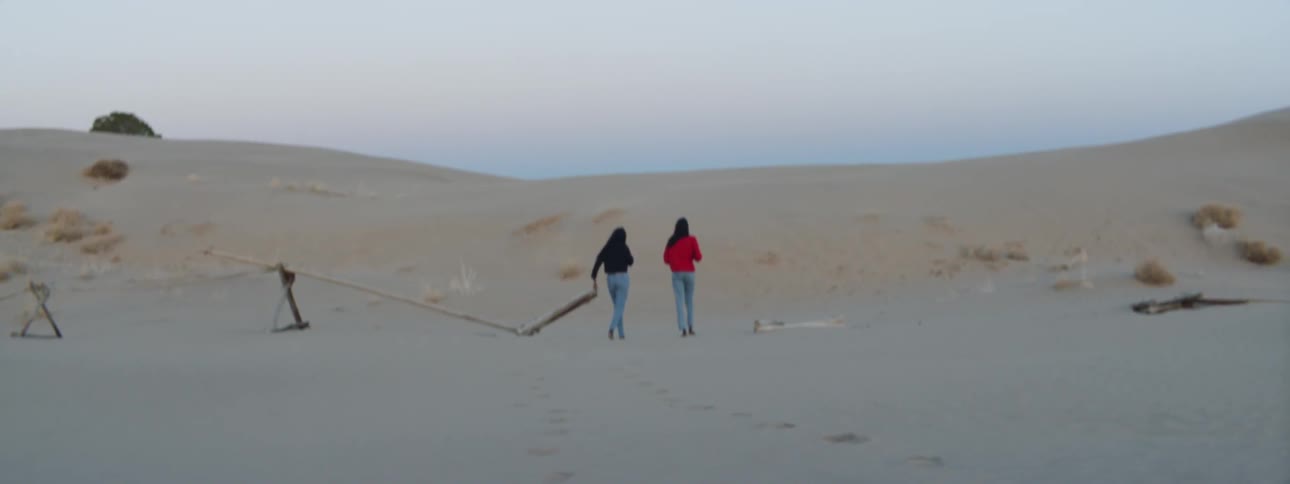 Two women that are walking together in the sand dunes