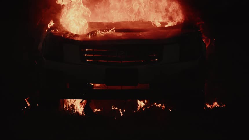 A car is completely up in flames and only the front bumper is visible