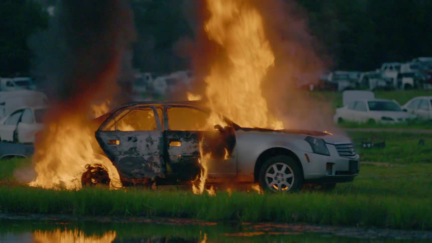 Car lot with car on fire and heavy black smoke