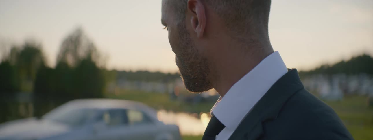 Man in suit outdoors while sun sets