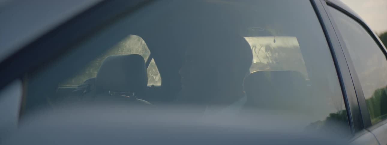 A man sitting in a car looking out the window