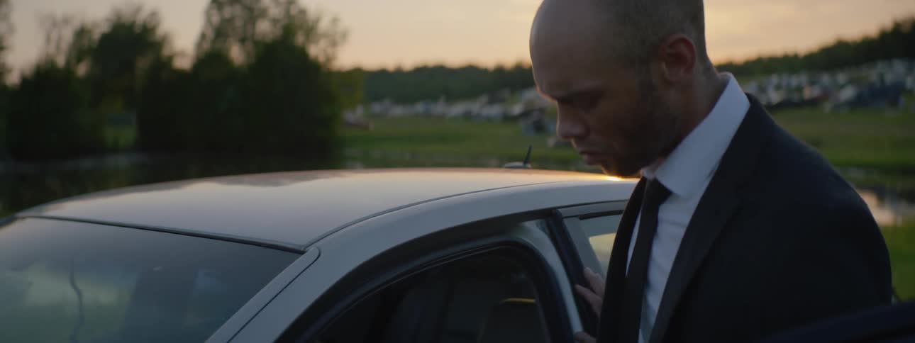 A man enters the driver seat of a car