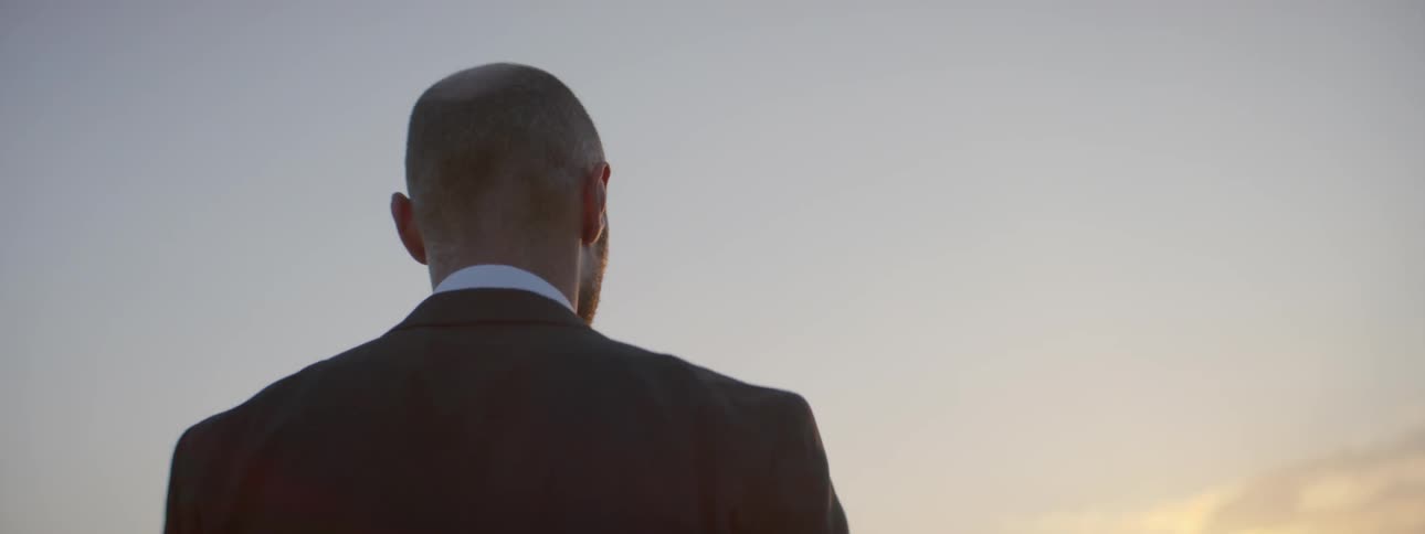 Man in a suit looking into the distance at sunset