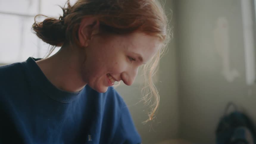 A woman looks down and laughs and talks to someone below her