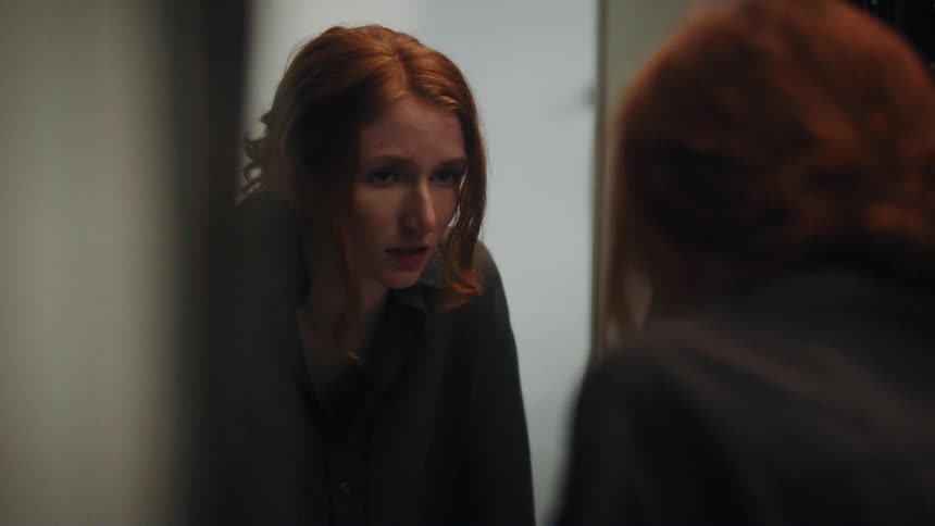 A woman looking in a mirror and moving her hair