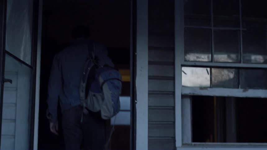 A boy walks into the front door of a house