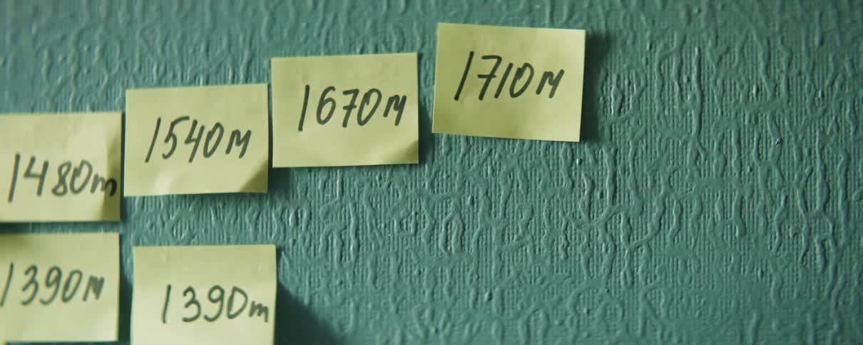 Hand places sticky note on green wall