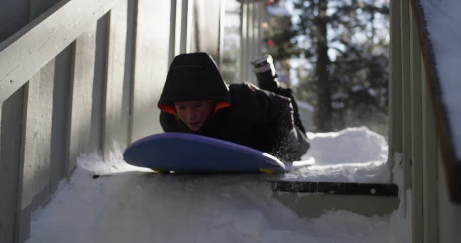 A child is sledding down the stairs