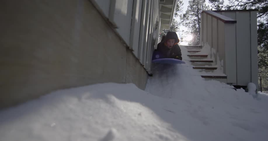 A kid is sledding down stairs