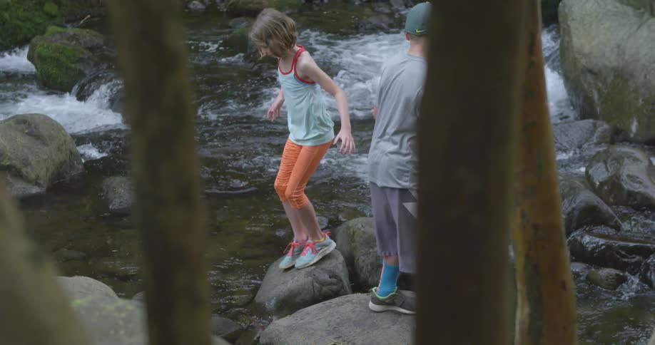 A boy  is walking up a stream
