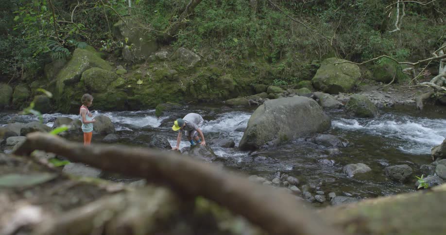 A person crosses a flowing river as a girl watches