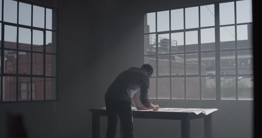 A man standing at a desk drawing on a piece of paper