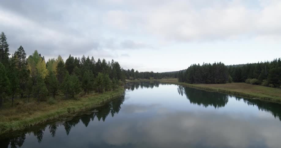 Time lapse of clouds passing over a small lake surrounded by trees