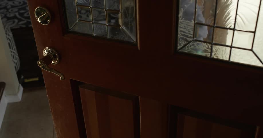 A child dribbling a basketball in the foyer and then out the door