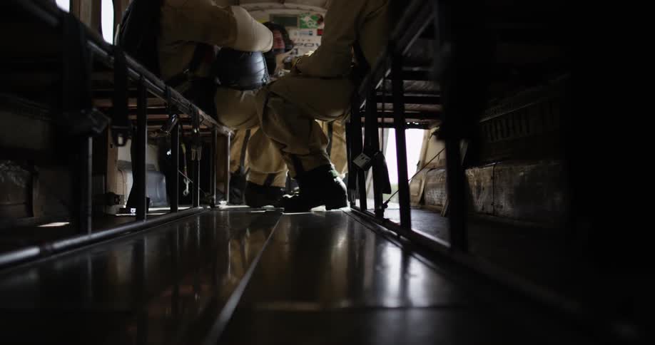 View of some men's feet and legs as they sit on a bench in an open plane