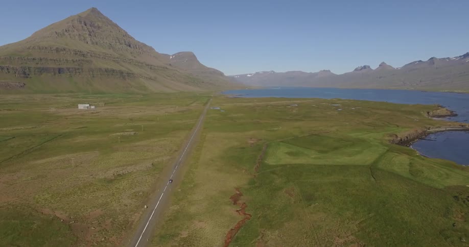 A vehicle driving towards a mountain lake
