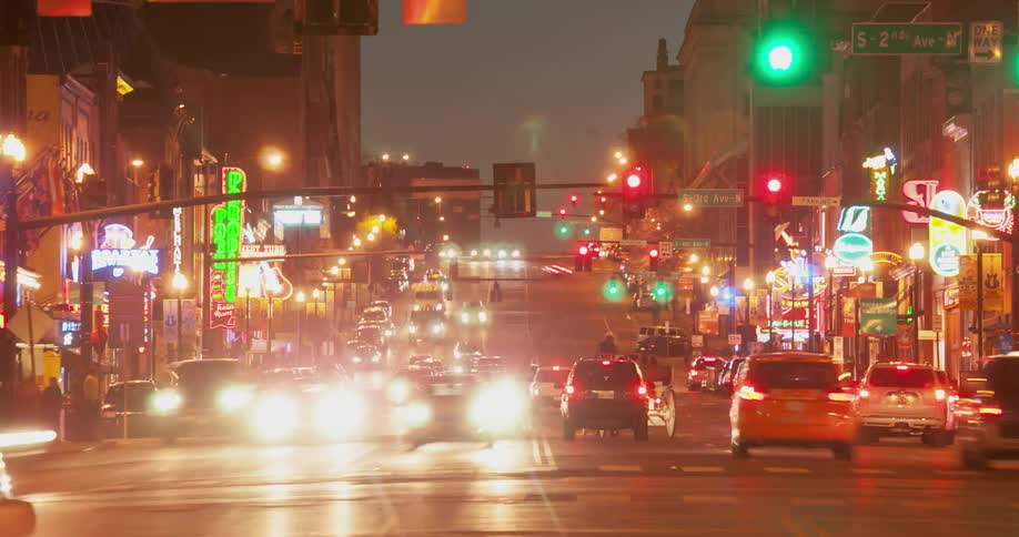 Traffic moves through a busy city intersection at night