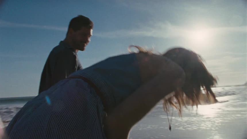 A man and woman holding hands on the beach