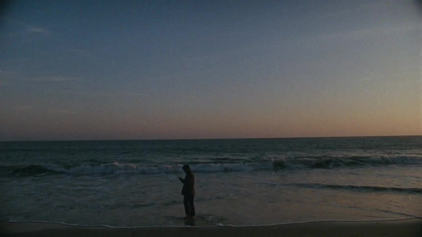 A man walking on a beach at sunset