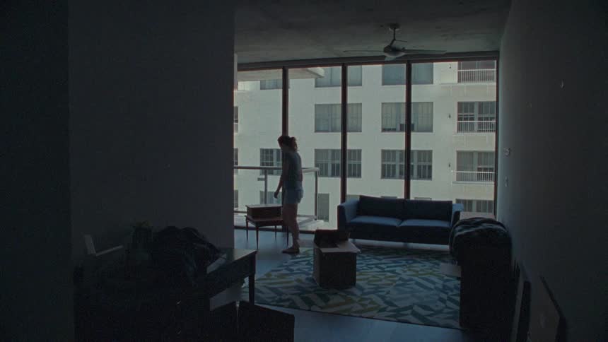 A woman moving a couch in a city apartment
