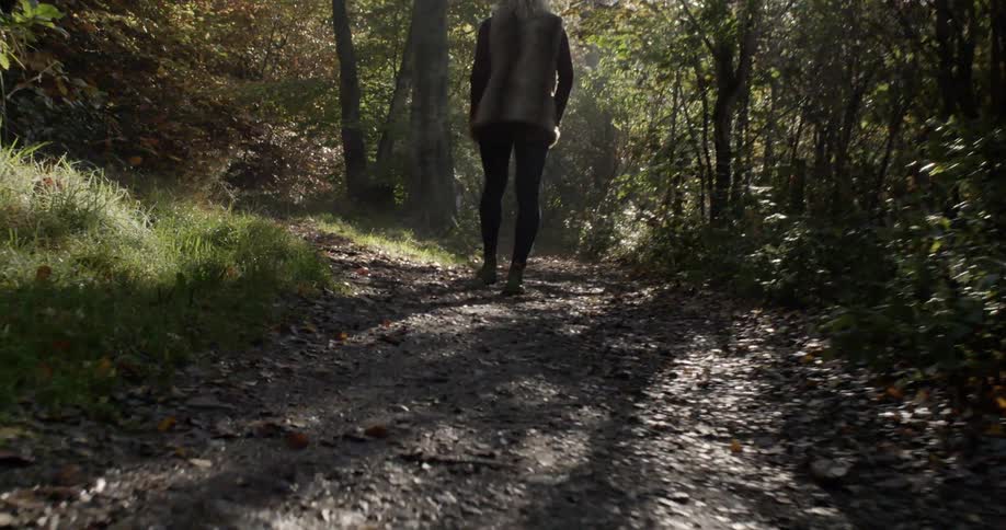 A woman walking down a forest trail