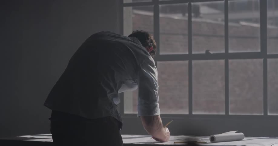 A man that is looking through some papers in front of a window