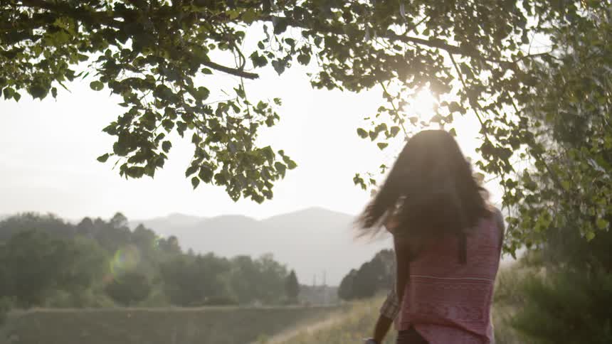 A woman swinging a baby around in a sunny field